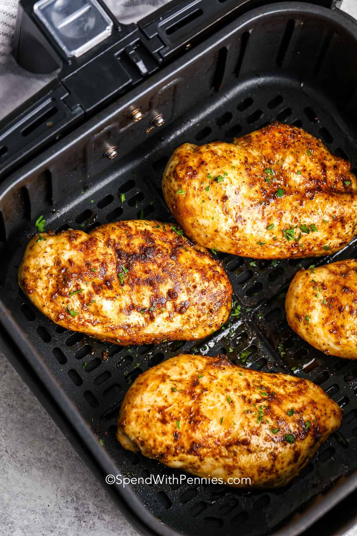 cooked chicken breasts in an air fryer basket