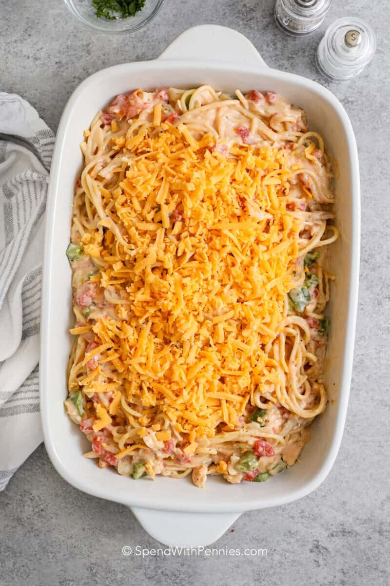 chicken spaghetti in a baking dish topped with cheese